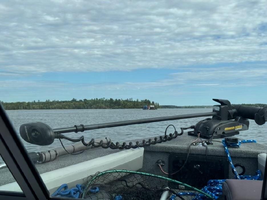 A barge in the distance across open water, seen past the boat's stowed trolling motor