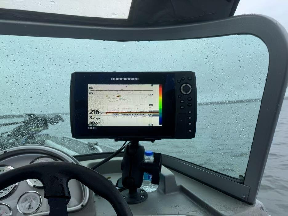 A Humminbird sonar screen reading 216.9 feet, seen through a rain-covered windshield